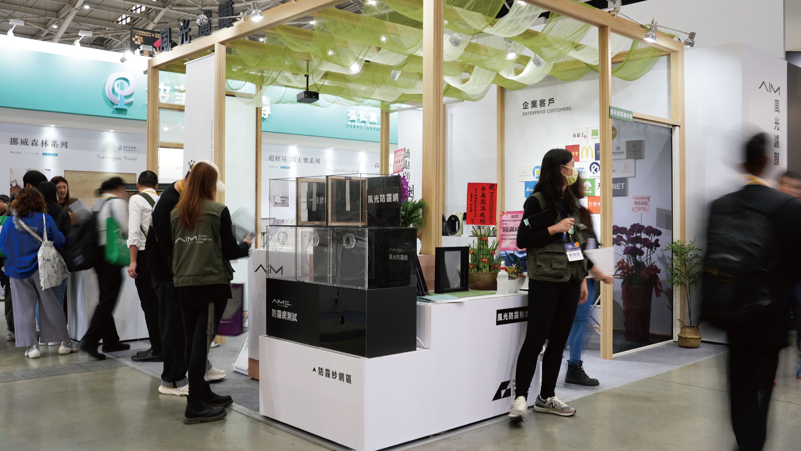 台北建材展風光集團攤位全景：AIM 風光濾膜與防霾網測試展示區，牆面陳列企業客戶標誌